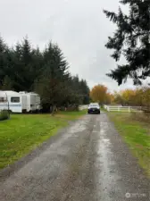 Facing down the gravel road going toward the property. This vacant land is on the right. It is  just before the residence at the end with the vinyl fence.