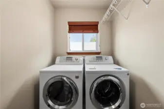 The upstairs laundry room comes with front-loading washer and dryer and features upper cabinets and a folding counter