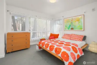 Primary bedroom. Bright light from windows that wrap the room.  Shown here are all cotton Voile draperies for soft light. At night draw the cellular shades for privacy. There is a dual closet on the side of the room not seen, fitted with interior sections.