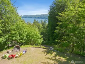 Lower cleared area is currently arranged for sunbathing and campfires, with ample space for additional activities or parking.