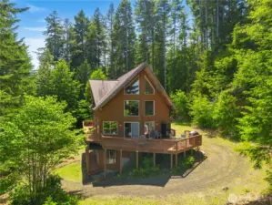 Expansive windows frame scenic views of the fjord and forested landscape.
