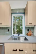 The kitchen window pulls nature in and is in sync with the calming natural palette of the home.