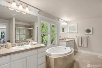 Spa-like primary bathroom with marble tiling, dual vanities, separate shower, and a large soaking tub! Green views from this space enable a quiet solitude.
