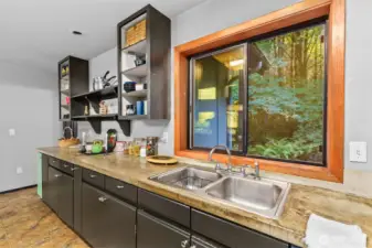 Open kitchen with double sink looking out over the wooded setting