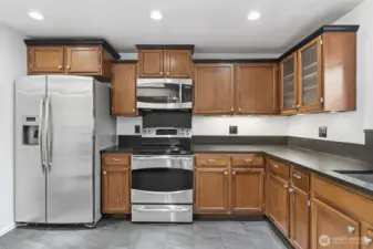 Spacious kitchen featuring stainless steel appliances, granite countertops, and rich mahogany cabinetry accented by under-cabinet lighting.