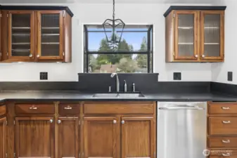 Sun-filled kitchen features a garden window perfect for herbs and plants, with a chandelier adding warmth and extra light.