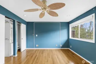 Bright primary bedroom with closet built-ins and a large picture window that welcomes abundant sunlight.
