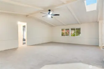 Another angle shows the skylight bringing in natural light, complemented by a new ceiling fan for comfort. Plush new carpet with 8lb padding and vapor barrier adds a soft touch underfoot.