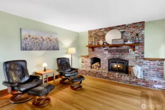 A cozy, crackling fireplace with a beautiful brick surround anchors the room, complete with a unique exterior hatch for convenient firewood access.