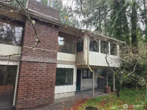 Back side of house opposite of entry. view shows kickout from Primary Bedroom, windows of living room and dining, lower bedroom patio and lower bonus room windows and sliding door.