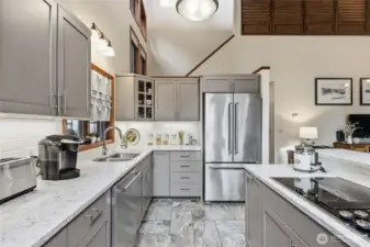A view of the kitchen looking toward the front of the house with the newer stainless steel refrigerator.