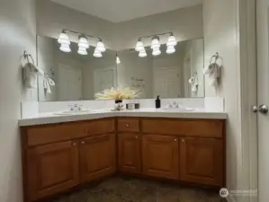 This main/guest bath impresses with its functionality, offering dual sinks for convenience and a private shower with a water closet through the door to the right, for added privacy.
