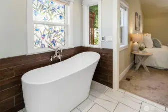 Relax in the freestanding soaking tub set beneath a sunny window—your personal at-home retreat.