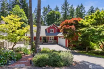 A storybook driveway leads to this vibrant, lovingly maintained home, embraced by mature trees and colorful landscaping.