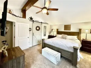 Updated primary with vaulted beamed ceilings, charming barn door leads to updated bath.