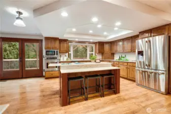 Open-concept kitchen with large center island, bar seating, double doors to the deck, and great flow into the dining and living spaces—built for everyday life and effortless entertaining.