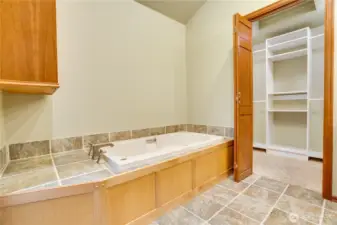 Jetted soaking tub in the primary ensuite, with tile surround and direct access to the walk-in closet.