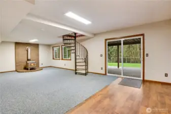 Daylight lower level with pellet stove, circular staircase, and slider to the patio and lawn—great as a media room, play space, or future guest suite.