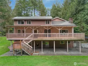 Full rear view of the home showcasing the expansive covered deck, lower patio, and big grassy yard—fantastic indoor-outdoor flow for gatherings, kids, and pets.