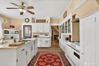 This kitchen just feels cozy and real. It has that authentic farmhouse character you want in an 1890 home, especially with the high-back vintage sink and all the original built-in cabinetry. The center island adds that modern functionality you need, but the whole space still keeps its charm, right down to the old-school white stove. It’s a warm, welcoming space where you’ll actually want to hang out.