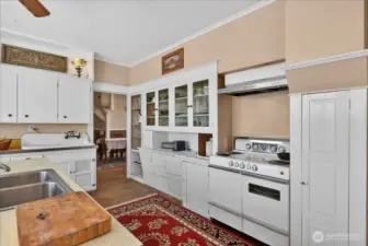 The kitchen flows right into the formal dining room. You get a great look at that classic high-back sink and all the built-in storage, including the extra pantry space tucked next to those glass-front cabinets. It perfectly captures that 1890 farmhouse character while showing off a layout that’s actually functional for everyday life. It’s easy to see why this has remained the heart of the home for 136 years.