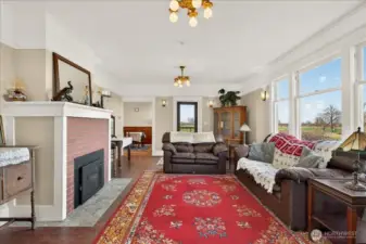 The living room is such a comfortable spot to sit back and take in the views. The brick fireplace adds that classic,  feel you want in an 1890 farmhouse, and the whole room feels bright and welcoming. You can see how it connects right to the dining area, and those large windows look straight out over the backyard with no neighbors in sight. It’s a peaceful and that’s been a central part of this home's 136-year history.