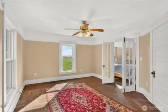 The light in this room gets with windows facing both East and North. It’s the perfect spot to catch the morning sun over the fields. Those French doors are such a great original feature, too—they open right up into the next room, which makes the whole space feel even bigger and more connected.