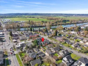 Aerial view of residential neighborhood with property marker, nearby river, and surrounding farmland.