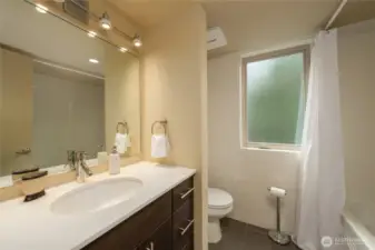 The full bathroom on the upper floor with a large frosted window that opens.