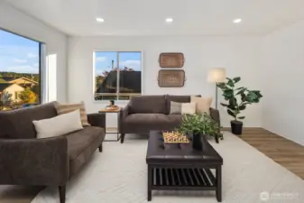 Living room with large picture windows, neutral wall tones, and seating area arranged on a soft woven rug.