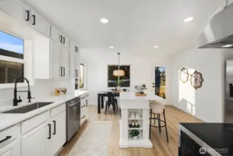 Bright kitchen featuring white cabinetry, quartz countertops, black hardware, and stainless steel appliances for a clean, modern look.
