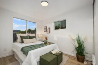 Light-filled bedroom with dual windows, neutral finishes, and a calming palette that complements the wood-look flooring.