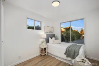 Secondary bedroom with large picture window, modern overhead lighting, and soft natural tones for a serene atmosphere.