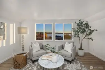 Upper-level sitting area with large windows capturing scenic views and space for a cozy seating arrangement.