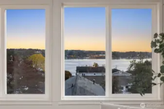 Expansive window view overlooking rooftops, trees, and the water beyond, capturing the natural beauty of the surrounding area.