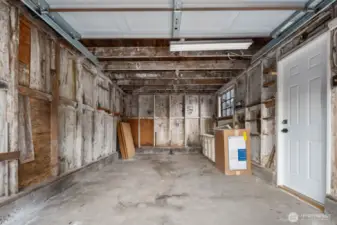 Single-car garage with exposed wood framing, shelving, and overhead lighting—offering flexible space for storage or projects.