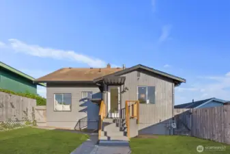 Back view of the home showing wood siding, a small porch landing, and fenced yard space.