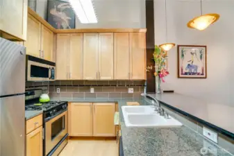 Gracie countertop. Double basin sink. Gas stove and glass pendant custom lighting. It’s feels like home here.