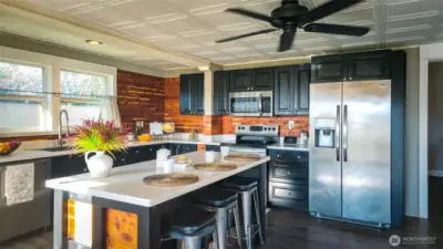 Sunlight pours into this newly updated kitchen, where modern finishes meet warm character. The large island anchors the space, offering room for everyday meals or casual gatherings, while stainless appliances and generous cabinetry keep everything within easy reach. Thoughtful updates make this kitchen both highly functional and inviting.