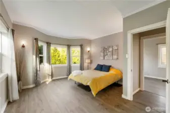The primary bedroom offers a spacious, airy feel with a layout that easily accommodates a full bedroom setup while still feeling open and uncluttered. Updated flooring and soft, neutral tones create a calm, comfortable backdrop, and the thoughtful layout allows for natural flow between the sleeping area and adjoining spaces.