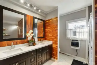 The updated bathroom features a modern vanity with clean lines and generous counter space, paired with warm wood accents that add character and contrast. Thoughtful lighting and contemporary finishes give the space a fresh, comfortable feel.