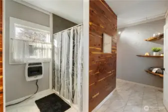 The bathroom includes a spacious shower with a bright, open feel, complemented by natural light and built-in raw edge shelving for storage. Warm wood details and clean tile finishes create a space that feels functional, comfortable, and well designed. Don't forget to check out the tankless water heater.