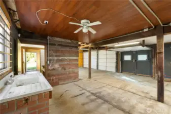 This image focuses on the utility sink and adjacent workspace, emphasizing the practical infrastructure of the garage. Hot and cold water service, combined with ample lighting, makes cleanup and task work convenient and efficient. There is even a ceiling fan.