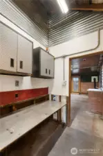 A dedicated workbench area with wall-mounted storage provides an organized setup for tools and supplies. The surrounding finishes and lighting reinforce the garage’s purpose as a true working space rather than simple storage.