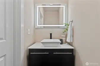 Modern half-bath on the main level with sleek vanity, vessel sink, and LED backlit mirror for a polished touch.
