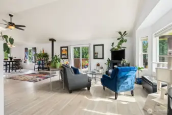 Walk in to an Open Concept Living Room with Big Bay Windows and a sliding glass door to the outside deck. Ceiling Fans and Wood Burning Fireplace for Seasonal Comfort
