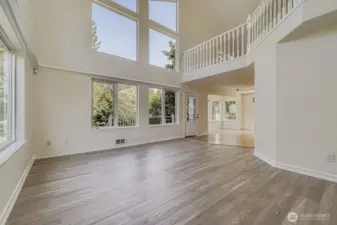 Large family/living room with expansive windows & views of treetops