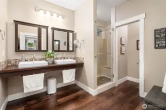 Step into a bathroom that’s all about clean lines and smart design. Suspended double sinks create a floating effect, paired with modern mirrors that hide built-in medicine cabinets for a clutter-free look. The glass-door shower lets in natural light from the upper window, while the separate toilet closet keeps privacy on point.