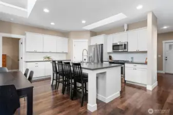 Unit B is on the main floor level as well and has 2400sqft of living space. The kitchen impresses with a large quartz island, white cabinetry, and classic subway tile backsplash. Skylights flood the space with natural light, while rich wood-tone vinyl plank floors keep it waterproof and stylish. Stainless appliances, a corner pantry, and a long beverage or baking counter complete this 9-foot ceiling beauty.