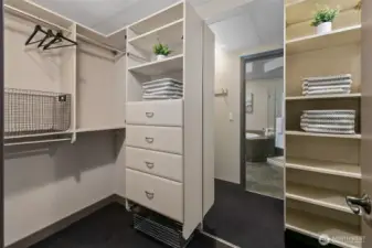 Large walk-in closet with built in closet system and floor-to-ceiling mirror.